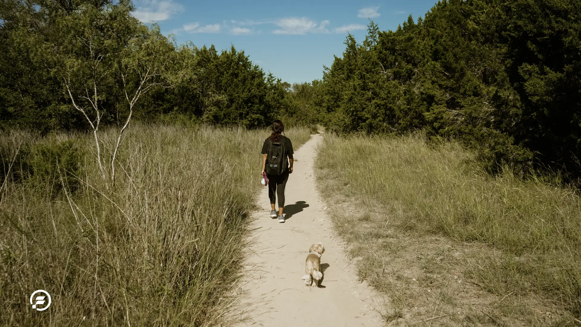 A woman and her shih-tzu on the trail.