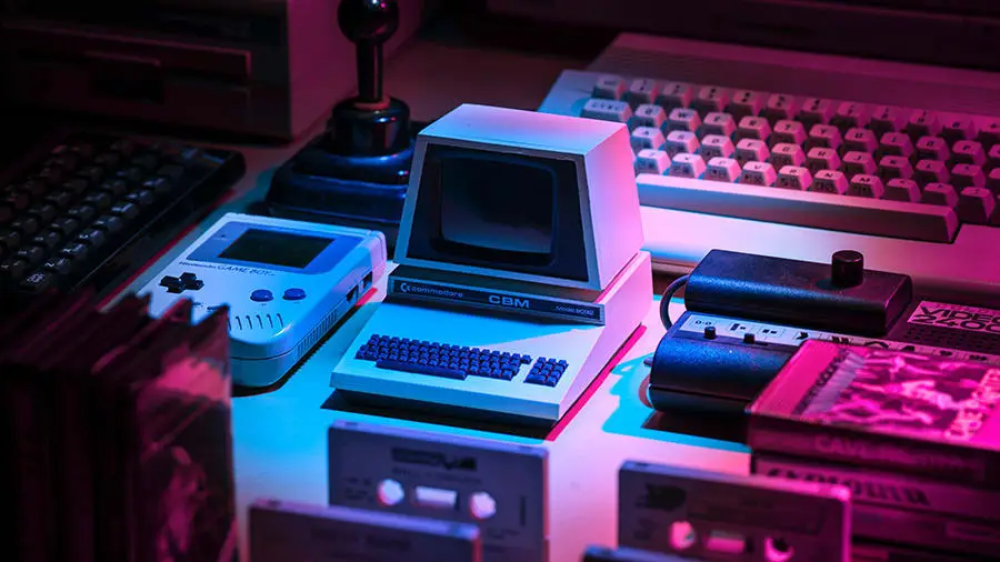 A retro 80's computer setup with purple lights cast upon it.
